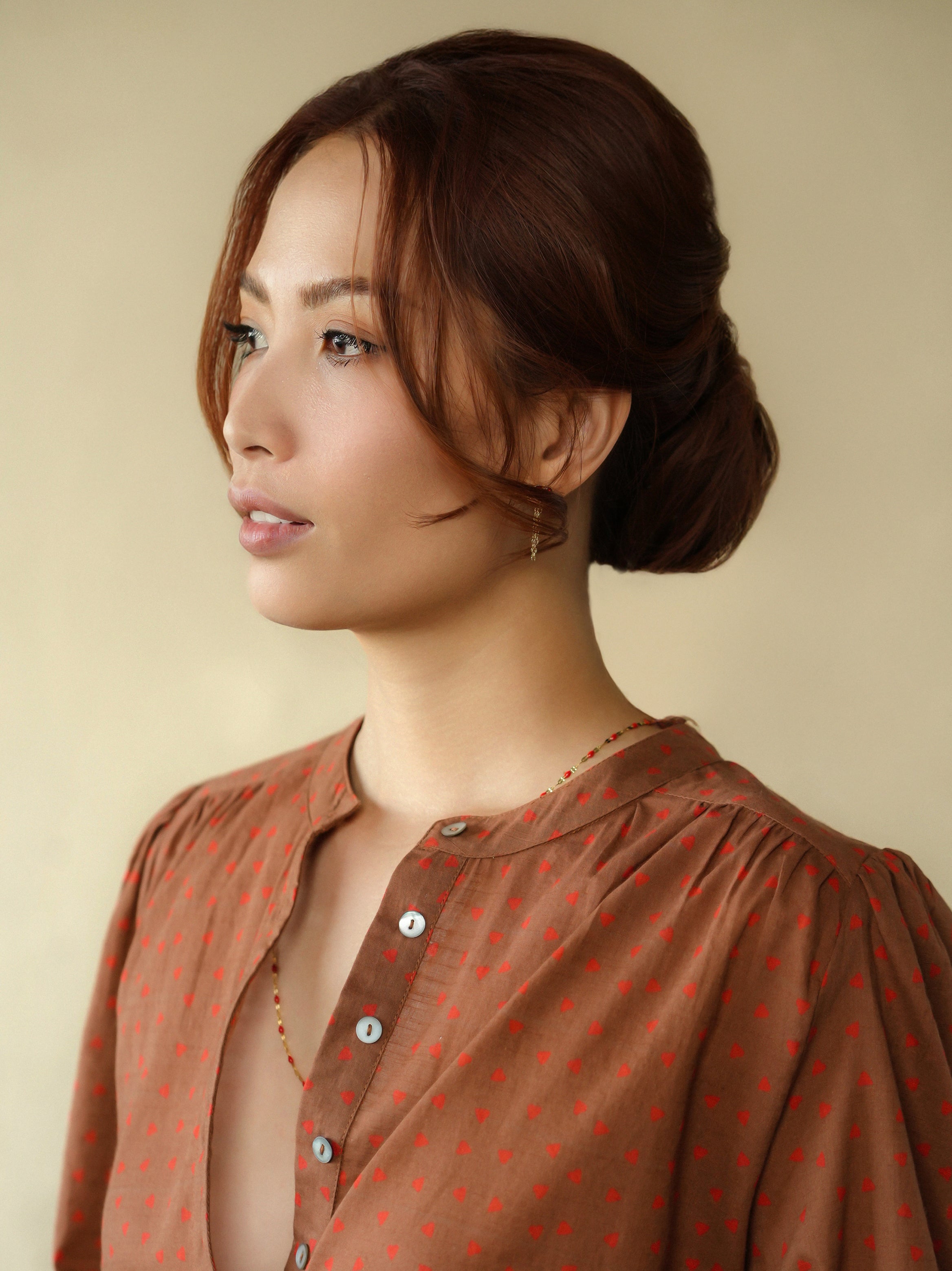 Woman wearing a brown patterned blouse against a beige background