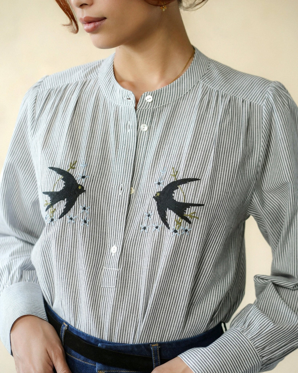Person wearing a striped shirt with swallow designs on a neutral background