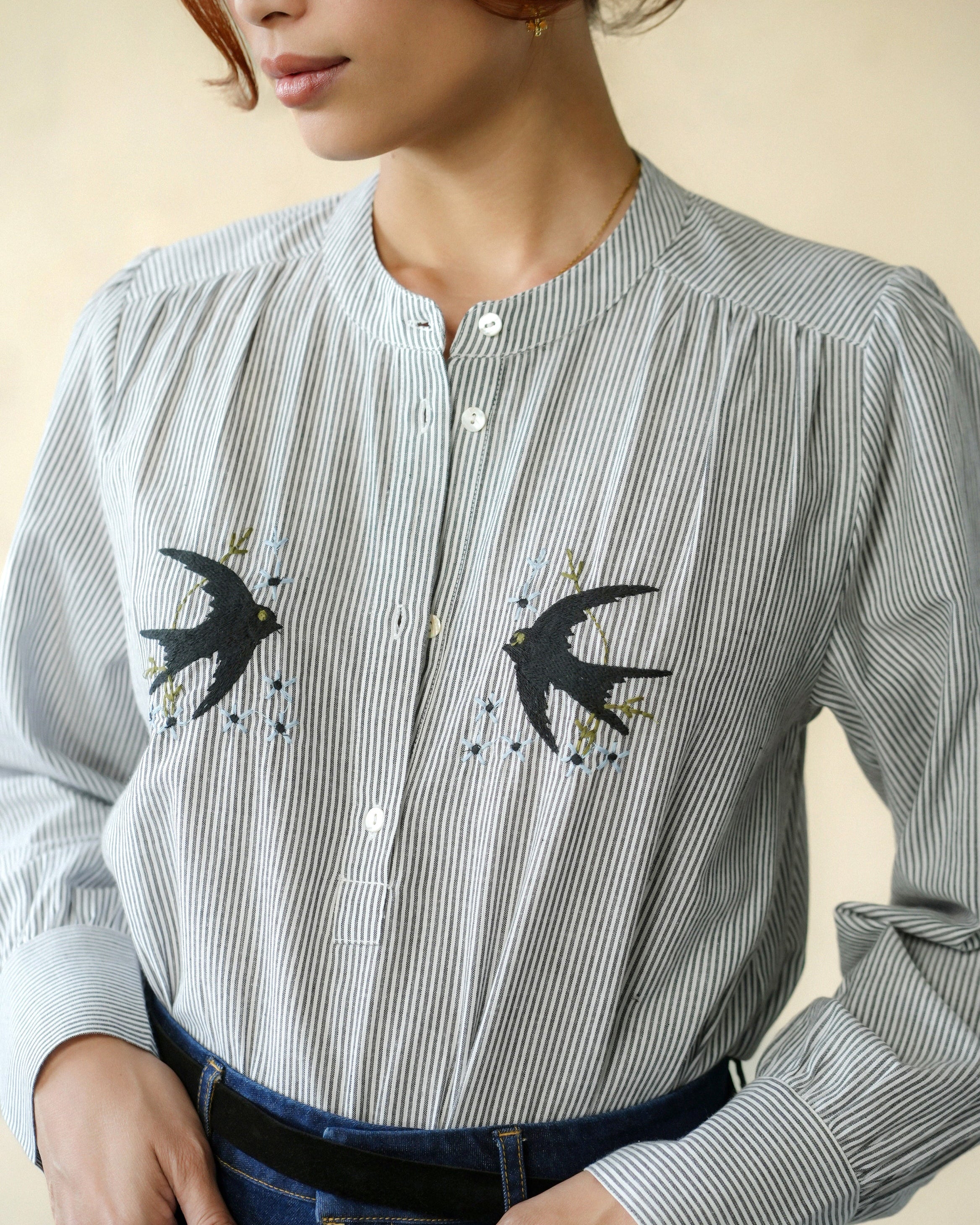 Person wearing a striped shirt with swallow designs on a neutral background